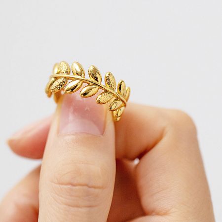Detailed studio shot of the stainless steel olive branch leaf ring in gold.