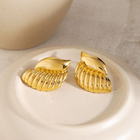 The set of 5 pairs of gold conch shell earrings presented on a white plate, showcasing their beach-inspired aesthetic.