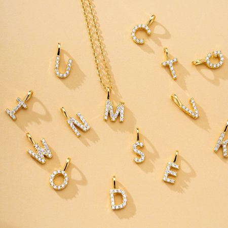 A collection of gold-plated alphabet pendants adorned with brilliant zircon stones.