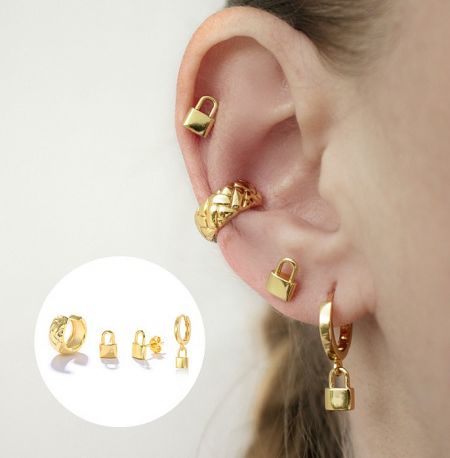 A model wearing the gold lock-shaped hoop earrings from the set of four.