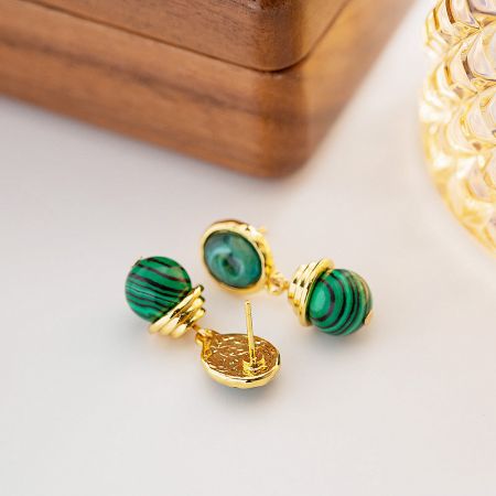 Detailed shot of gold-plated earrings with beautiful green malachite stones, highlighting the natural patterns.