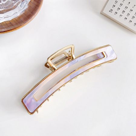 Close-up of a beautiful mother-of-pearl style acetate hair claw with a polished gold metal clamp.