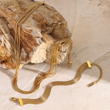 Detailed shot of the multi-strand gold chain design of the necklace and bracelet.