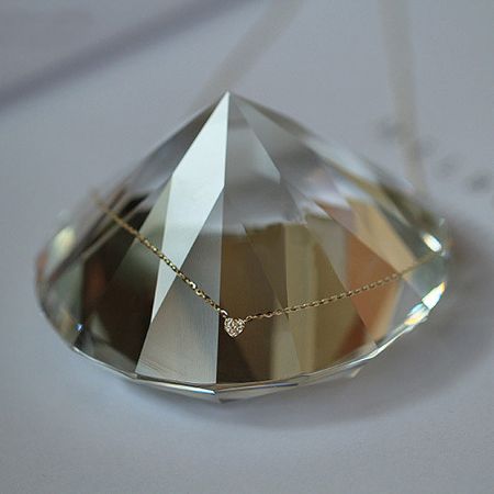 The gold heart pendant necklace elegantly displayed on a crystal, emphasizing its luxurious quality.