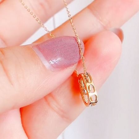 The oval pendant held in hand to show scale and craftsmanship.