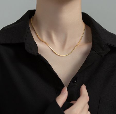 Close-up detail of the gold-plated 925 sterling silver flat snake chain necklace, highlighting its texture and shine.