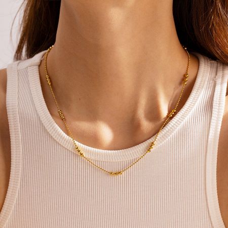 Detailed view of the 18k gold-plated beaded necklace on a model.
