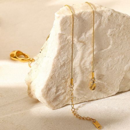 Detailed view of the geometric pendant necklace displayed on a textured stone.