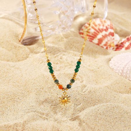 French-style sun pendant necklace with colorful beads displayed on a sandy beach.
