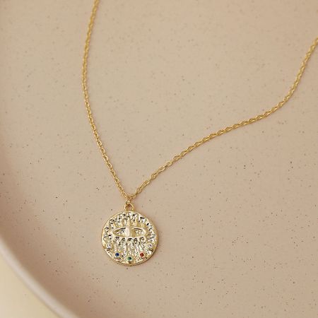 Close-up detail of the circular evil eye pendant with its intricate design and colored gemstones.