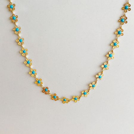 A detailed product shot of the gold necklace with turquoise flower-shaped beads.