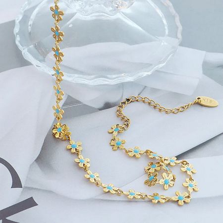 The full length of the gold necklace with delicate turquoise flower charms laid out.