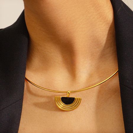 Detailed shot of the gold necklace with its unique half-circle pendant design.