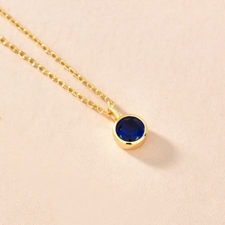 A stunning zodiac birthstone necklace in gold with a deep blue zircon stone.