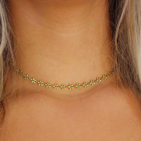 Detailed shot of the chamomile flower charm necklace on a plain background, highlighting the blue enamel.