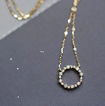 Detailed view of the zircon-studded circular pendant on its delicate sterling silver chain.