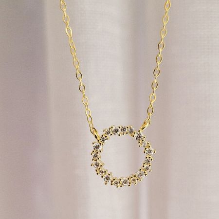The circular wreath pendant necklace shown against a neutral background to highlight its craftsmanship.