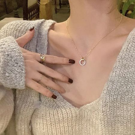 A close-up view of the zircon double-circle pendant on the gold necklace.