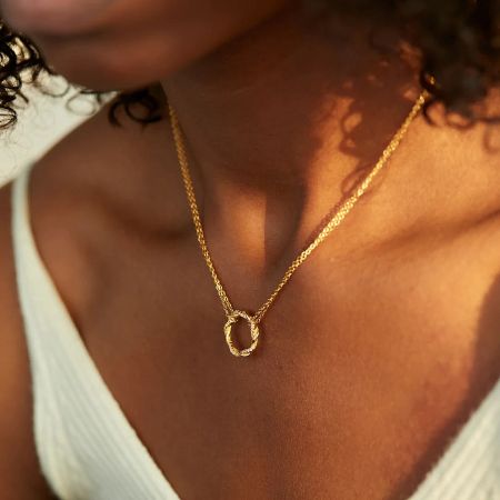 The Twisted Circle Zircon Necklace worn to complement a stylish outfit.
