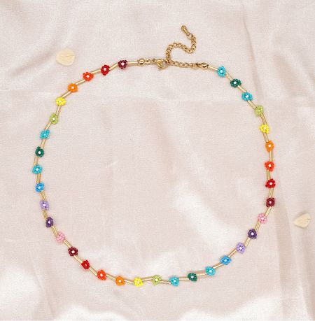 Beaded Flower Necklace - Close-up of the Beaded Flower Necklace JRN-069, showcasing its gold chain and vibrant, colorful flower-shaped beads on a light pink fabric background.