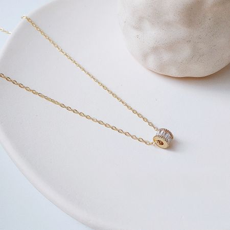 Close-up of a delicate gold necklace featuring a brilliant crystal pendant.