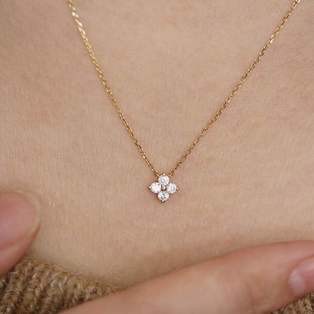 Detailed view of the sparkling zircon stones on the four-leaf flower charm.