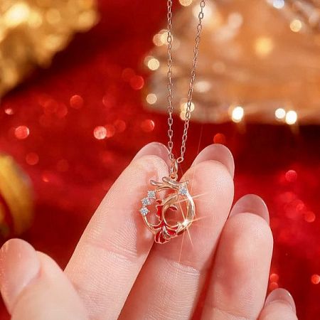 A delicate gold necklace with a sparkling diamond-studded pendant held for display.