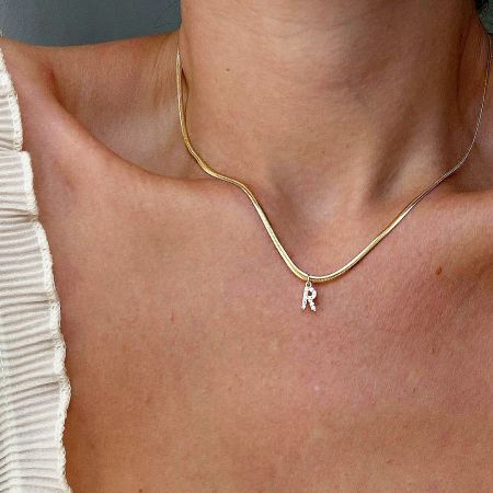 Close-up of a model wearing the gold initial necklace with a sparkling 'R' pendant.