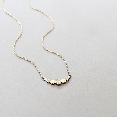 Close-up of the pendant with alternating gold balls and clear gemstones.