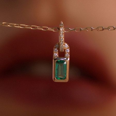 Close-up view of the gold necklace showcasing the intricate green zircon lock pendant.