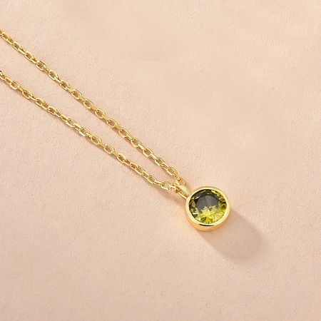 Close-up of a gold zodiac necklace featuring a vibrant green zircon birthstone.
