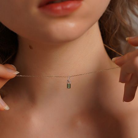 Side view of a model wearing the green zircon lock pendant necklace, highlighting its length and style.