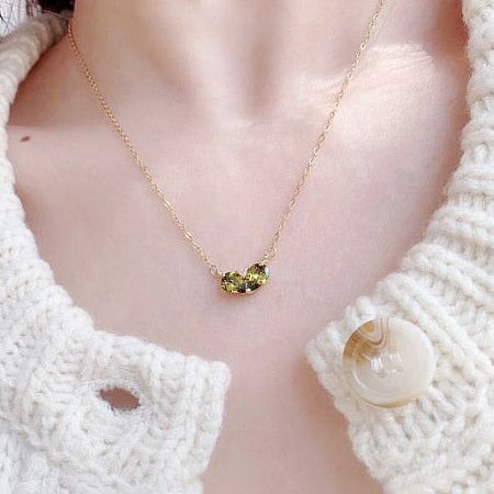 Detailed view of the gold-plated heart pendant with green emerald stones.