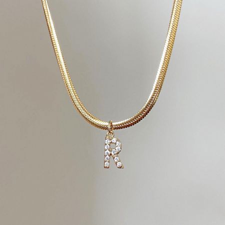 Detailed view of the elegant 'K' initial pendant on a gold snake chain.