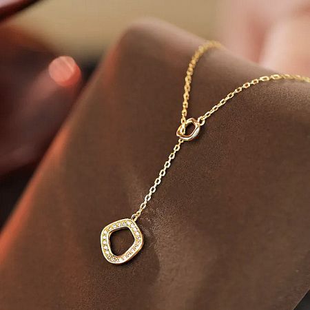 Gold geometric circle necklace on a white background.