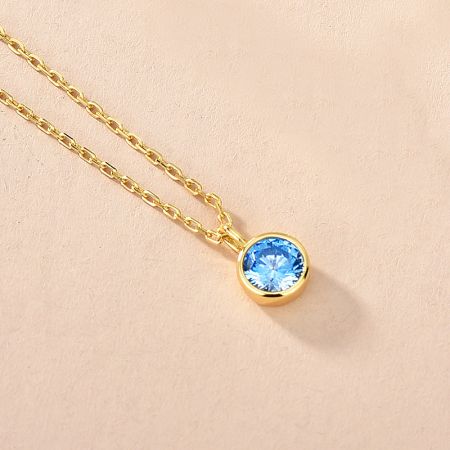 Detailed view of a 925 sterling silver necklace with a light blue zircon, representing a birthstone.