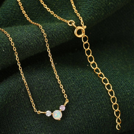 A delicate gold necklace featuring a shimmering opal and crystal pendant.
