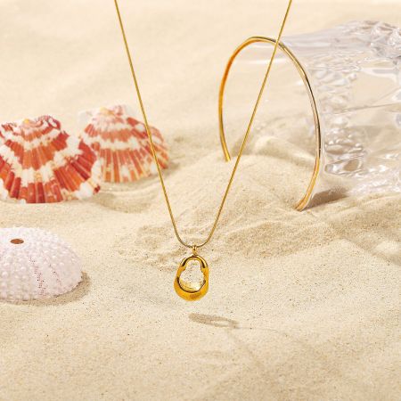 Lifestyle image of the gold-tone oval pendant necklace in a beach setting.