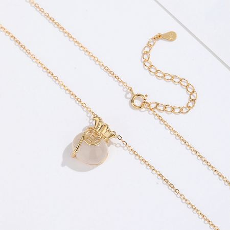 A gold necklace from the collection with a large, round, pale stone pendant, highlighting its elegant simplicity.