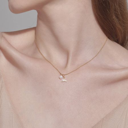 Gold necklace with a delicate star pendant and a single pearl.