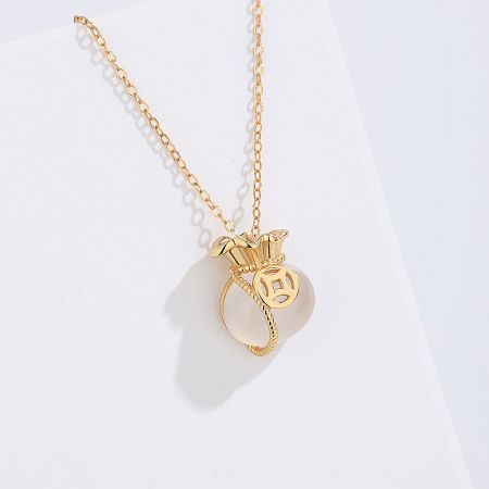 Detailed view of a gold necklace from the set, featuring a pearl pendant with a crown-like design.