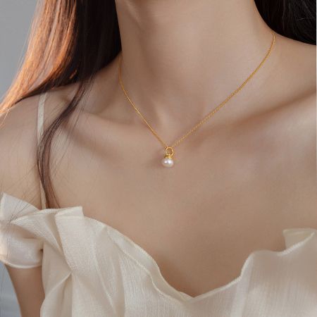 A model wearing the gold single pearl vintage necklace, showcasing its length and style.