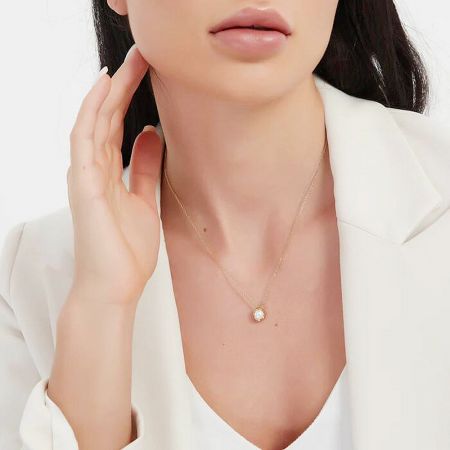 A model showcasing the elegant drape of the irregular pearl necklace against a white top.
