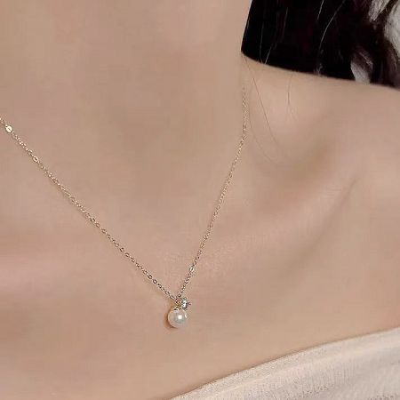 The gold pearl necklace shown against a neutral background.