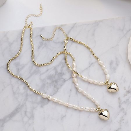 Another perspective of the gold necklace with pearls and heart pendants.