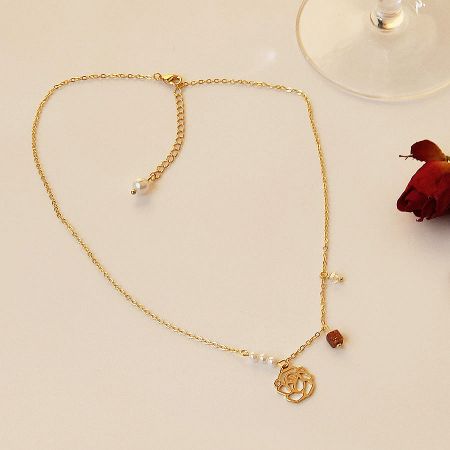 La catena della collana d'oro con piccole perle bianche e una perla centrale.