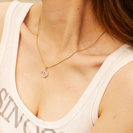 Detailed shot of the gold flower pendant, showing the intricate craftsmanship and polished finish.