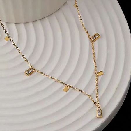 Close-up detail of a gold necklace from the set featuring rectangular clear stone charms.