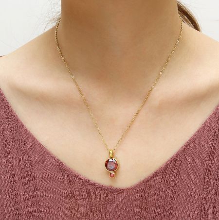 Close-up of the gold-plated necklace with a vibrant fire red cubic zirconia pendant.