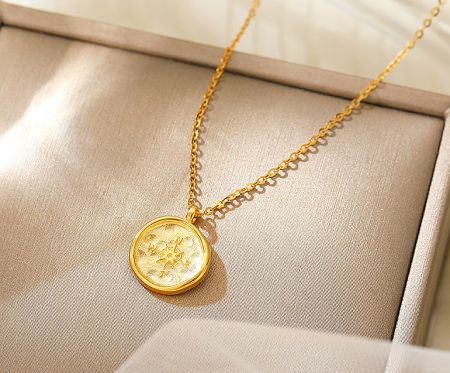 A close-up view of the gold compass pendant necklace, highlighting the intricate star-like design.
